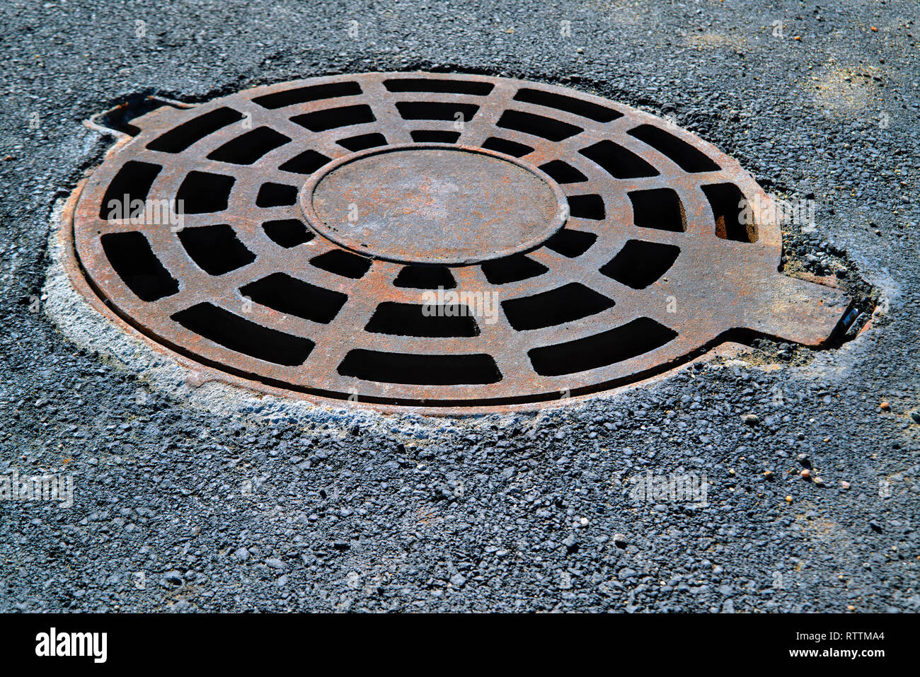 Cast-iron manhole cover storm sewer in the park close-up Stock Photo