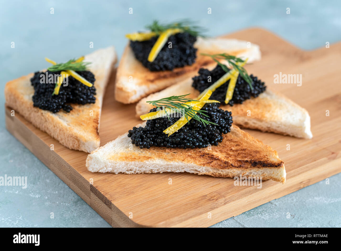 Appetizer toast bread with black caviar decorated by lemon pill and dill Stock Photo