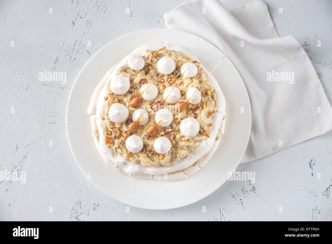 Pavlova cake with caramel and almonds on the wooden background Stock Photo