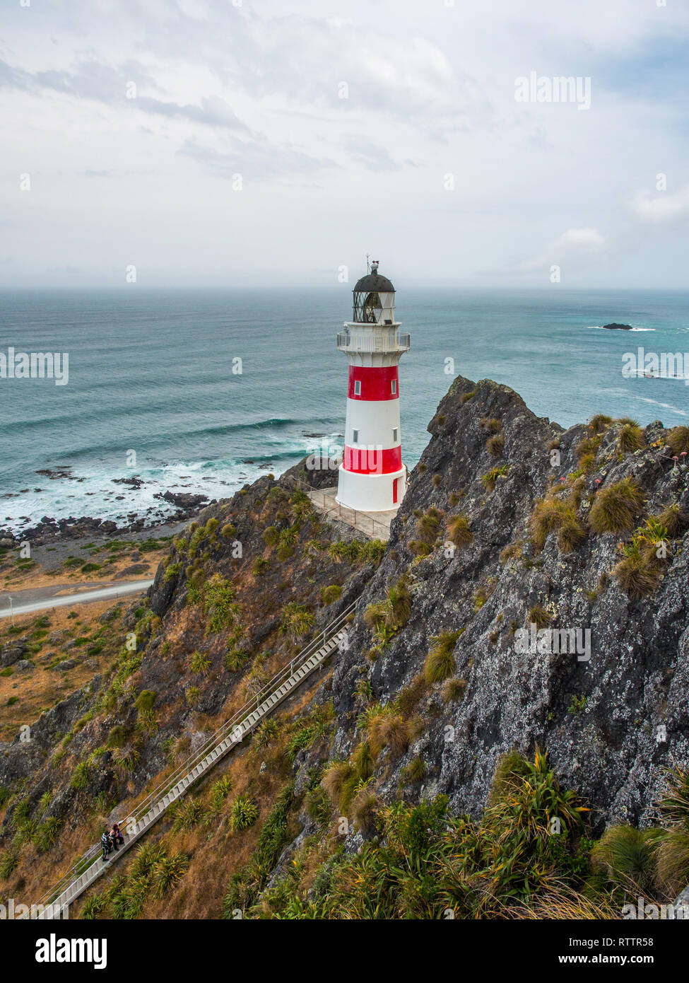 Looking down on 2 people,  climbing steep long row of stairs,  up to Cape Palliser lighthouse, Palliser Bay, Wairarapa, New Zealand Stock Photo