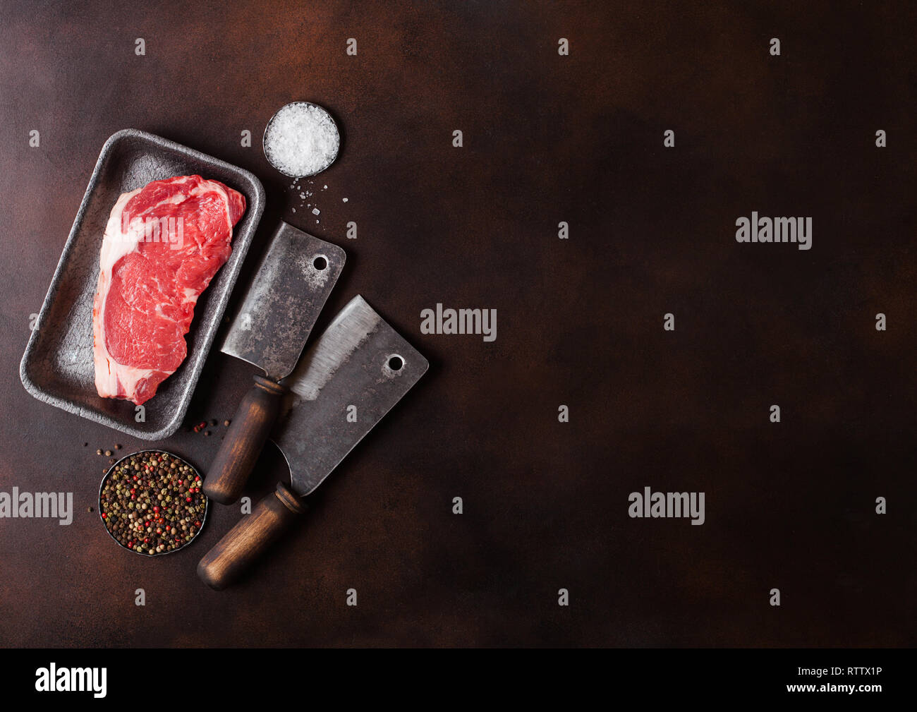Raw sirloin beef steak in plastic tray with salt and pepper and vintage ...