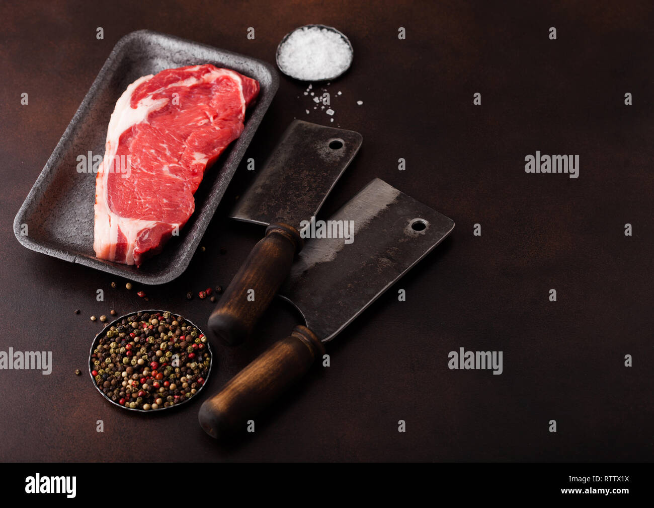 Raw sirloin beef steak in plastic tray with salt and pepper and vintage ...