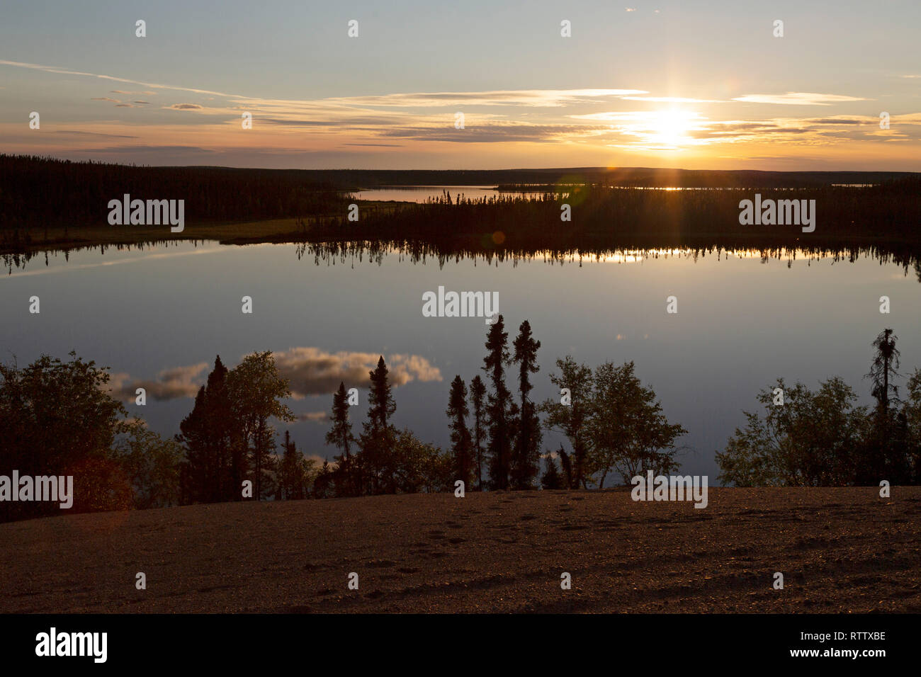 Sundown over Dillabough Lake in northen Manitoba, Canada. The sun reflects on the surface of the lake. Stock Photo