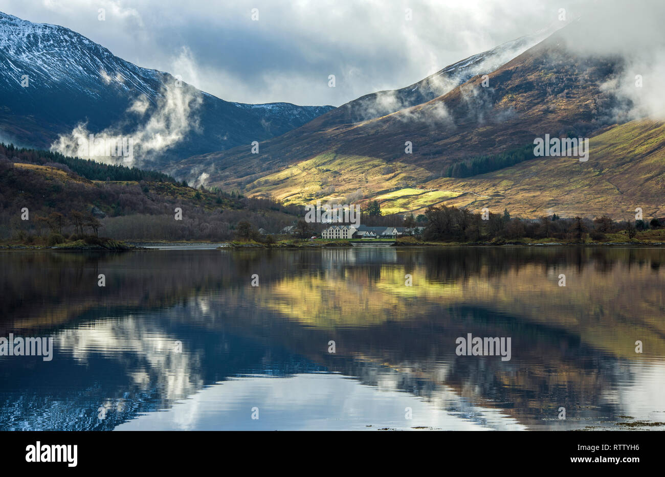 Clear reflections of the mountains and trees on Loch Leven, Glencoe, on a beautifully lit winter day in February. Stock Photo