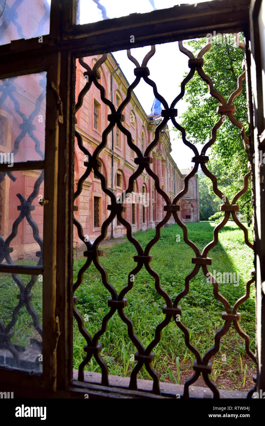 Inside derelict Invalidovna building in Karlín area of Prague looking out through grated window into courtyard. Building to be restored as cultural ce Stock Photo