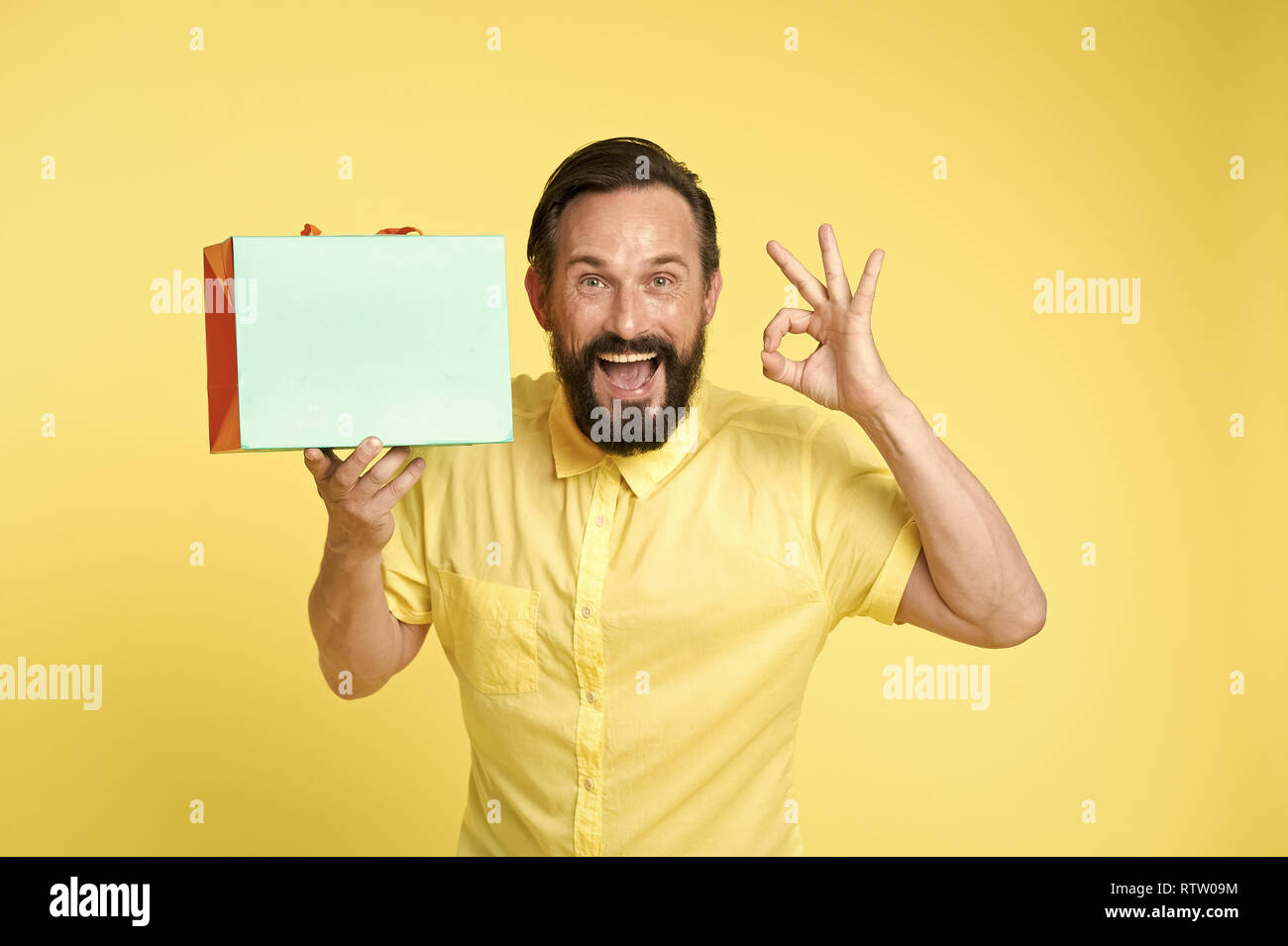 presenting your product. happy man hold shopping bag and presenting product. copy space play for presenting product. man with ok gesture presenting product Stock Photo