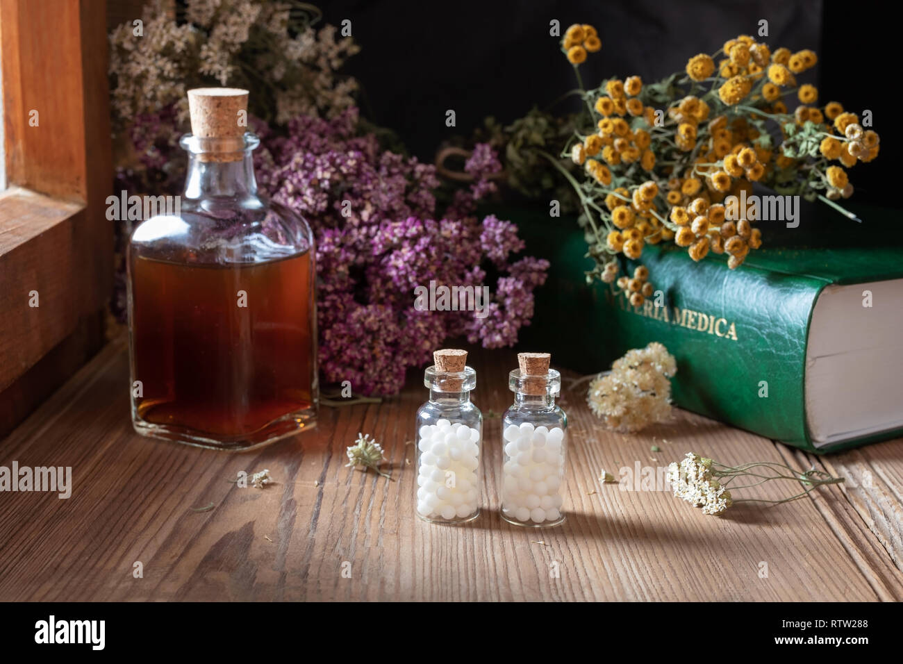 Two bottles of homeopathic globules with dried herbs and a materia