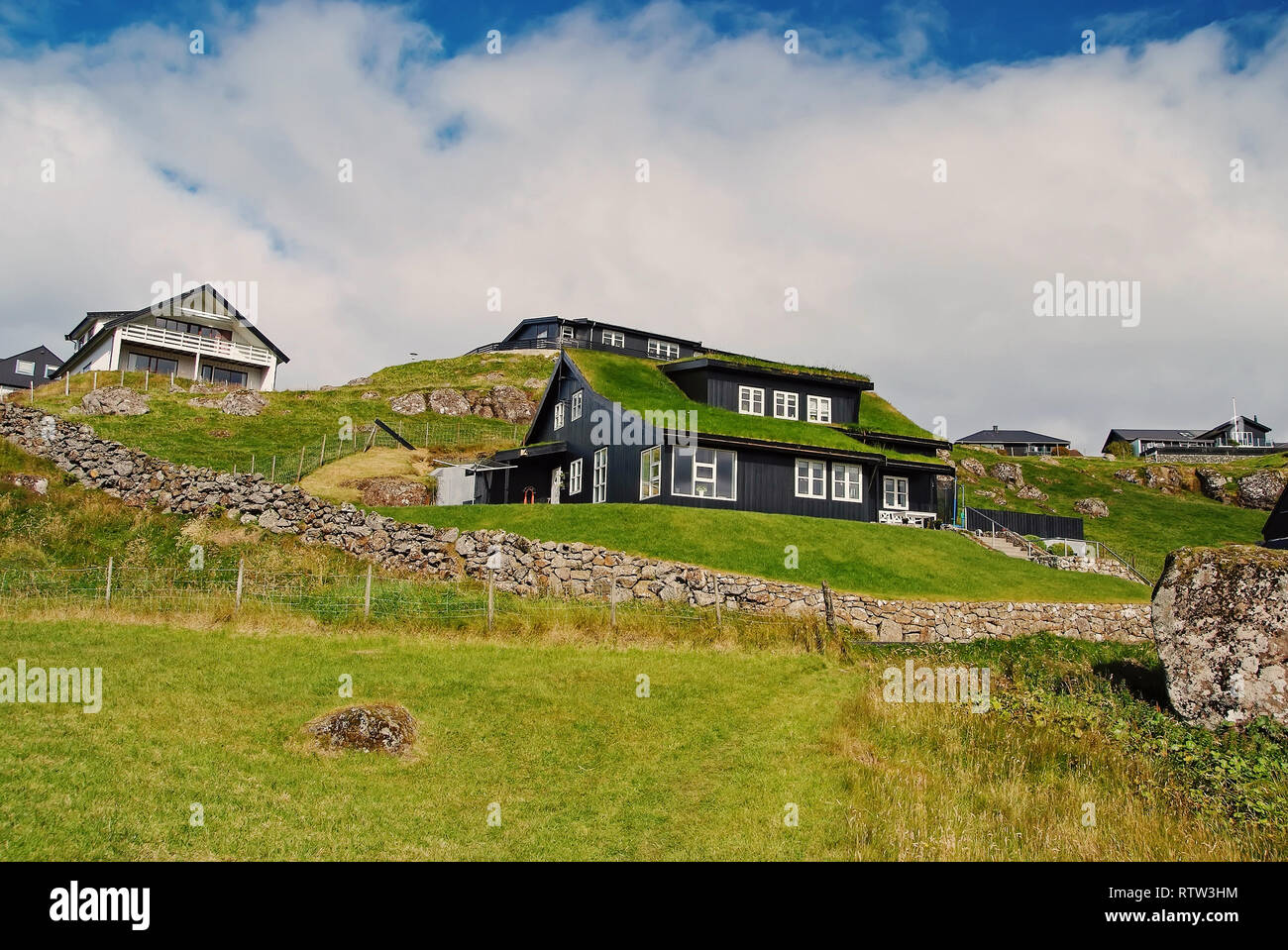 Houses on hilly terrain in Torshavn, Denmark. Eco friendly buildings on natural landscape on cloudy sky. Architecture and design. Ecology and environment. Summer vacation in countryside. Stock Photo