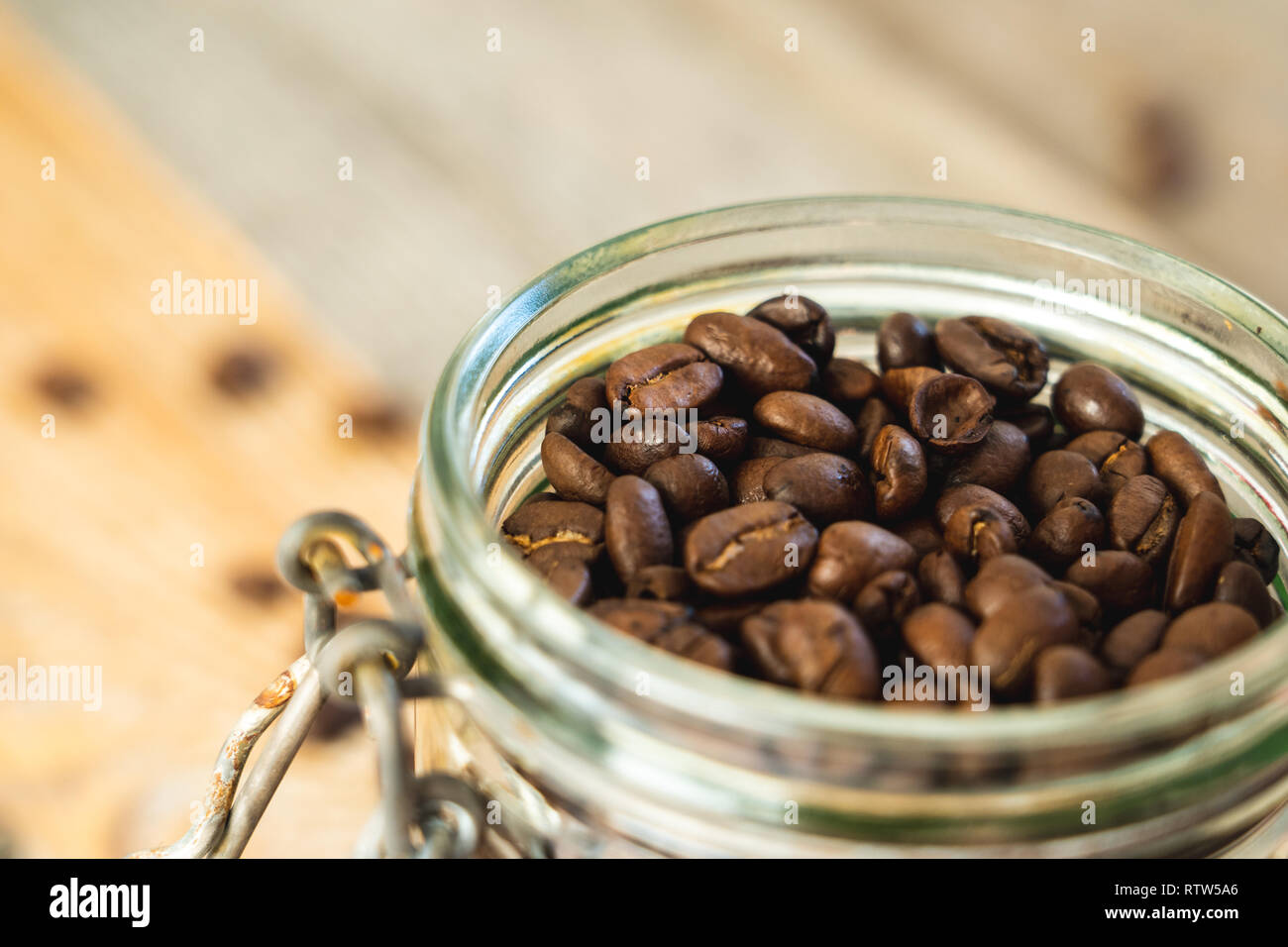 Top view of a glass jar filled with coffee beans on rustic wooden boards Stock Photo