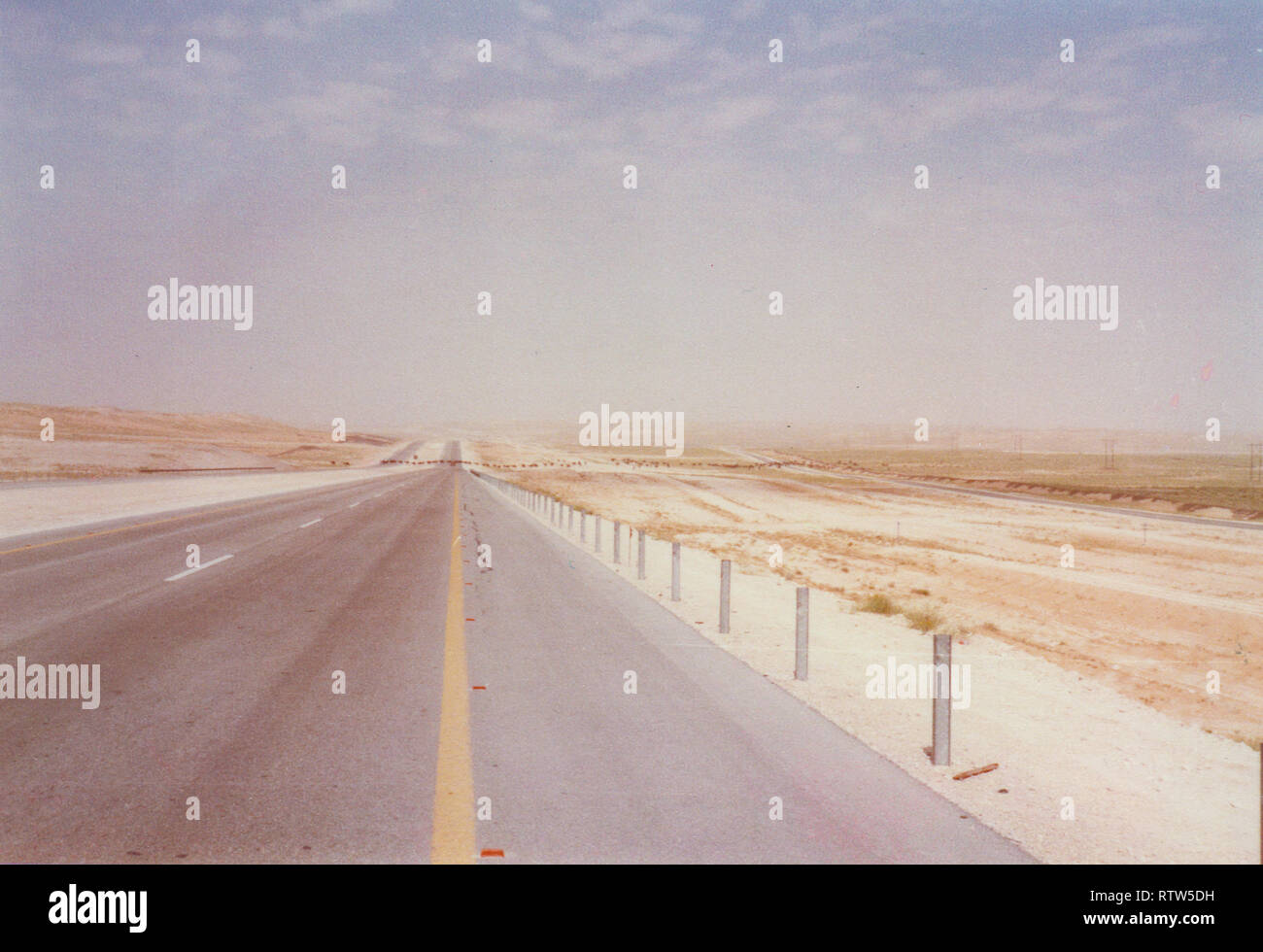 The road from the Abqaiq, a Saudi Aramco camp, to Qarrayah Beach, the town's closet private beach. The road is filled with sand dunes and often has camel herds driven by shepherds. Stock Photo