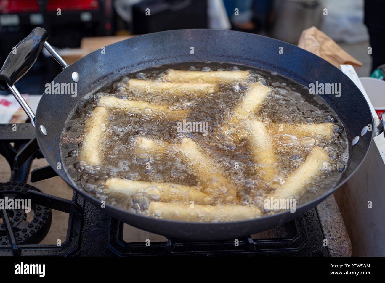 Spring rolls deep frying in hot boiling oil in a wok Stock Photo