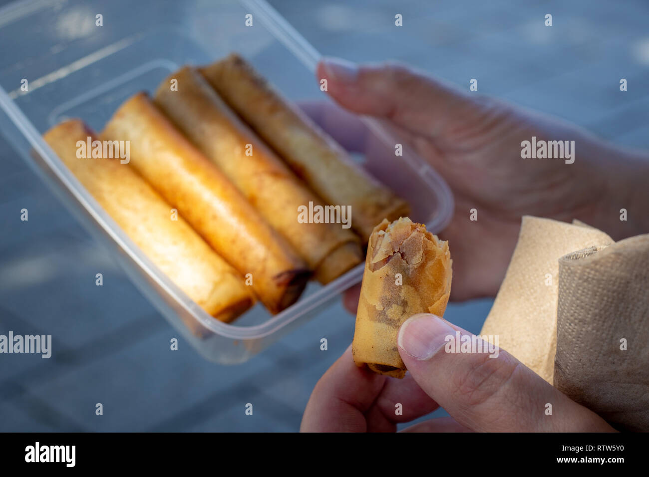 A man samples spring rolls at a food market in Christchurch, New Zealand - focus on the one being eaten Stock Photo