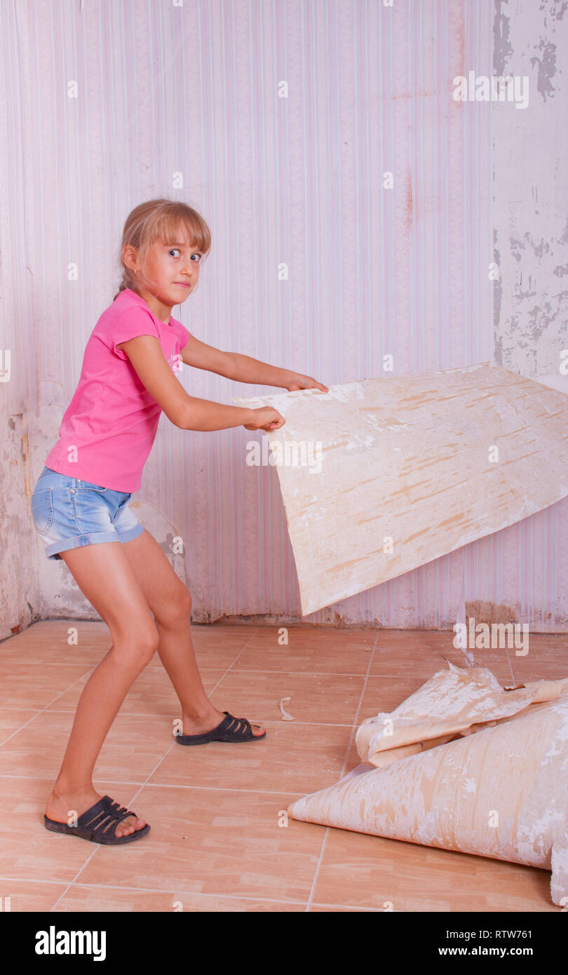 girl remove old wallpapers from wall Stock Photo