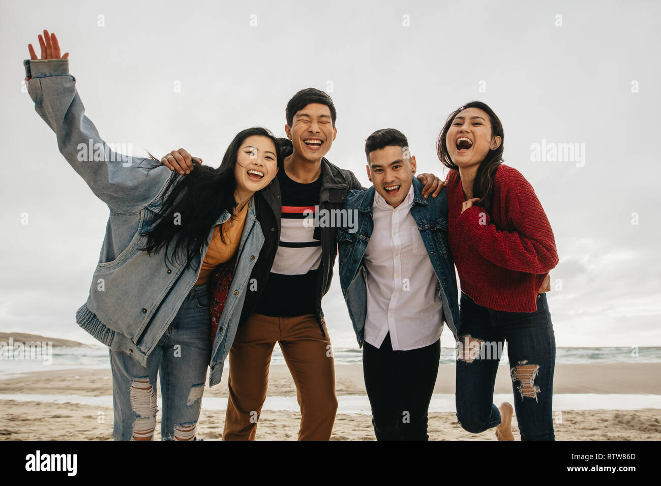 Group of asian friends on the seashore. Young people having great time together at the beach. Stock Photo