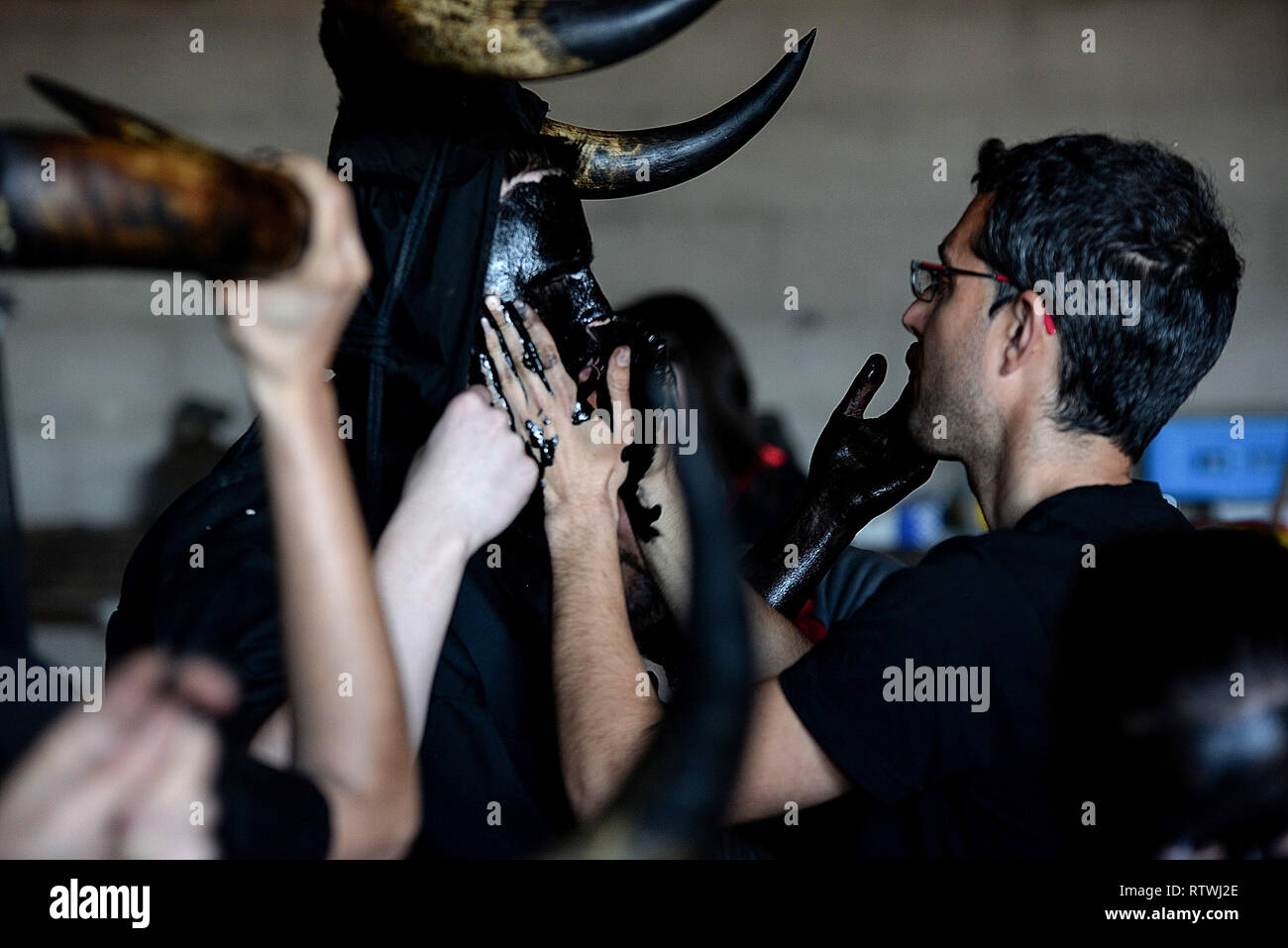 A reveller seen being dressed in oil, bull horns and cowbells to represent the devil, during a traditional carnival celebration in the small village of Luzon, Spain. Preserved records from the 14th century document Luzon's carnival, but the real origin of the tradition could be much older. Carnival festivals are celebrated in their own way around hundreds of villages in Spain. Stock Photo