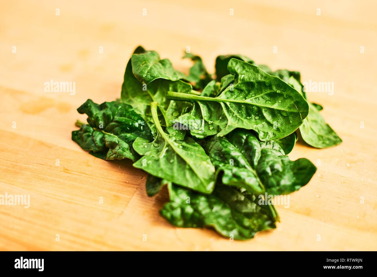 Fresh spinach leaves with water drops on wooden table. Top view with copy space for text. Stock Photo