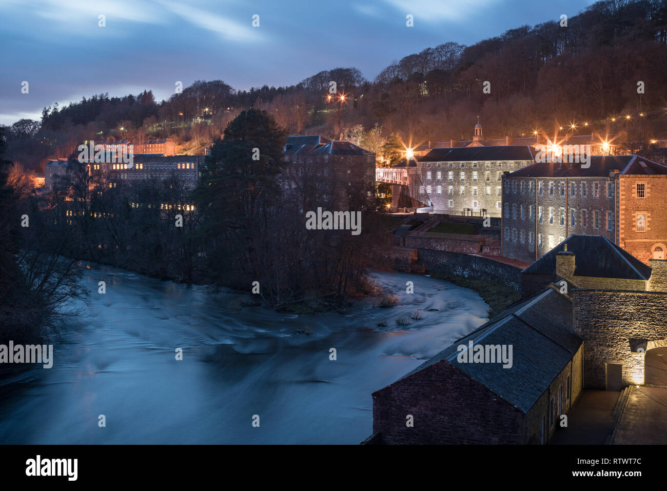 New Lanark Work Heritage Site seen at night showing buildings illuminated and lights showing in windows Stock Photo