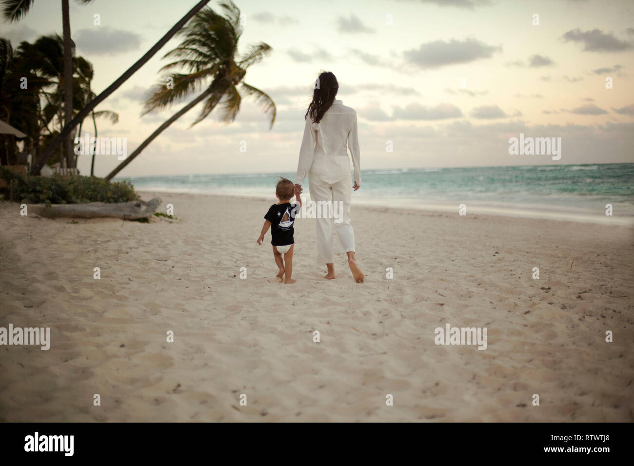 Mother and beby girl walking on tropical beach Stock Photo
