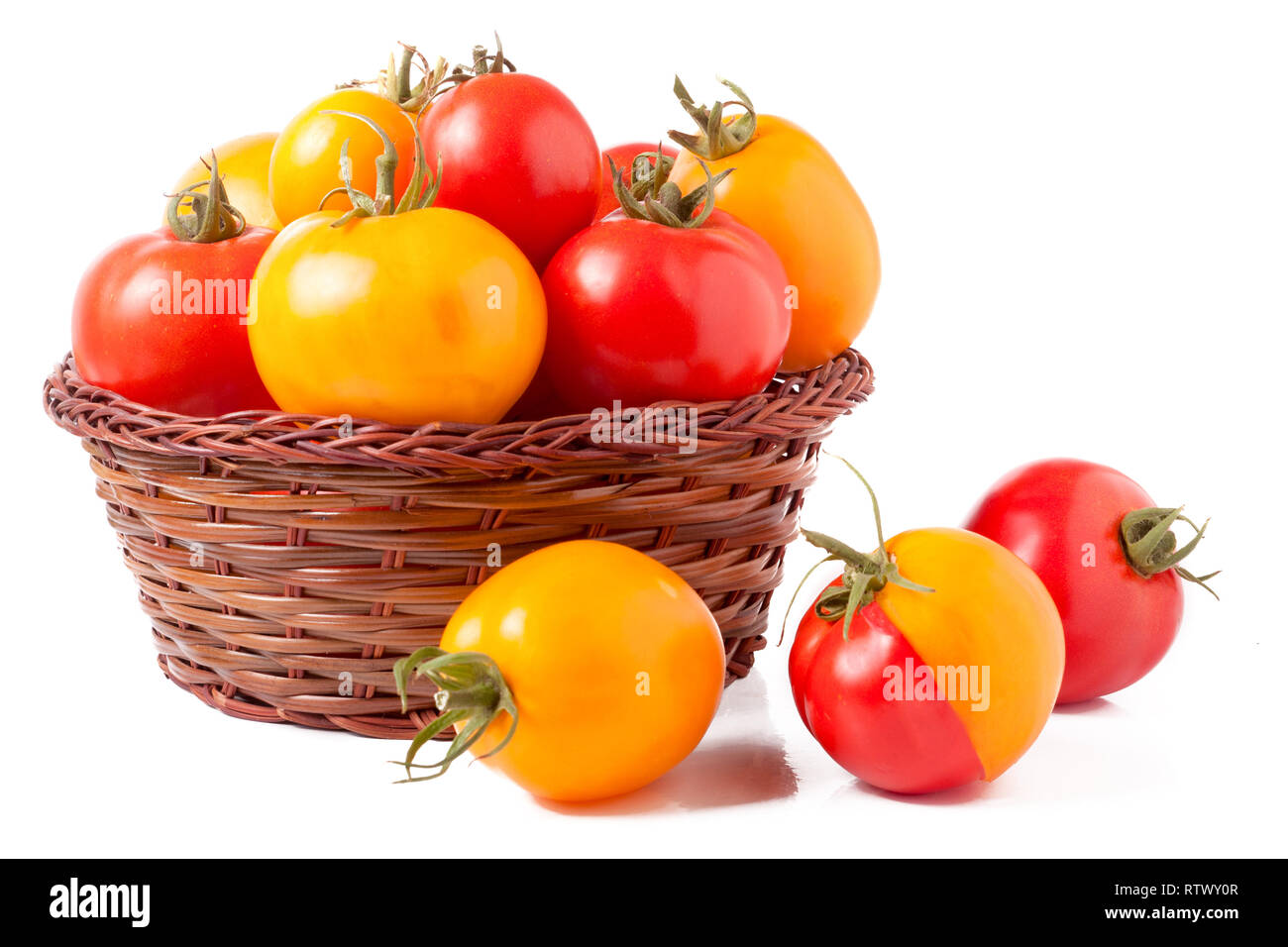 red and yellow tomatoes in a wicker basket isolated on white background ...