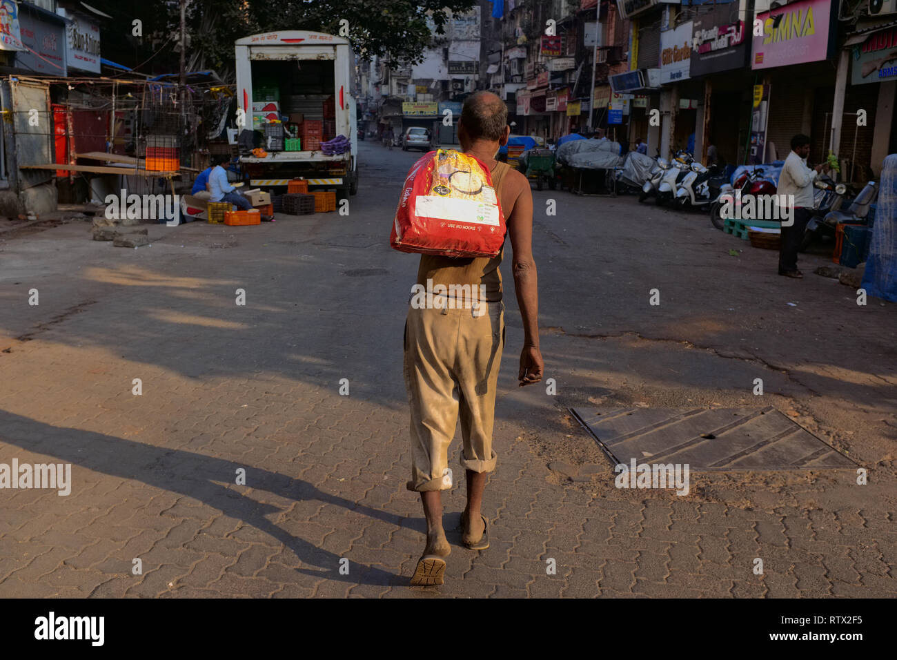 A homeless, shabbily dressed man walking the streets of Bhendi Bazar area in Mumbai, India Stock Photo