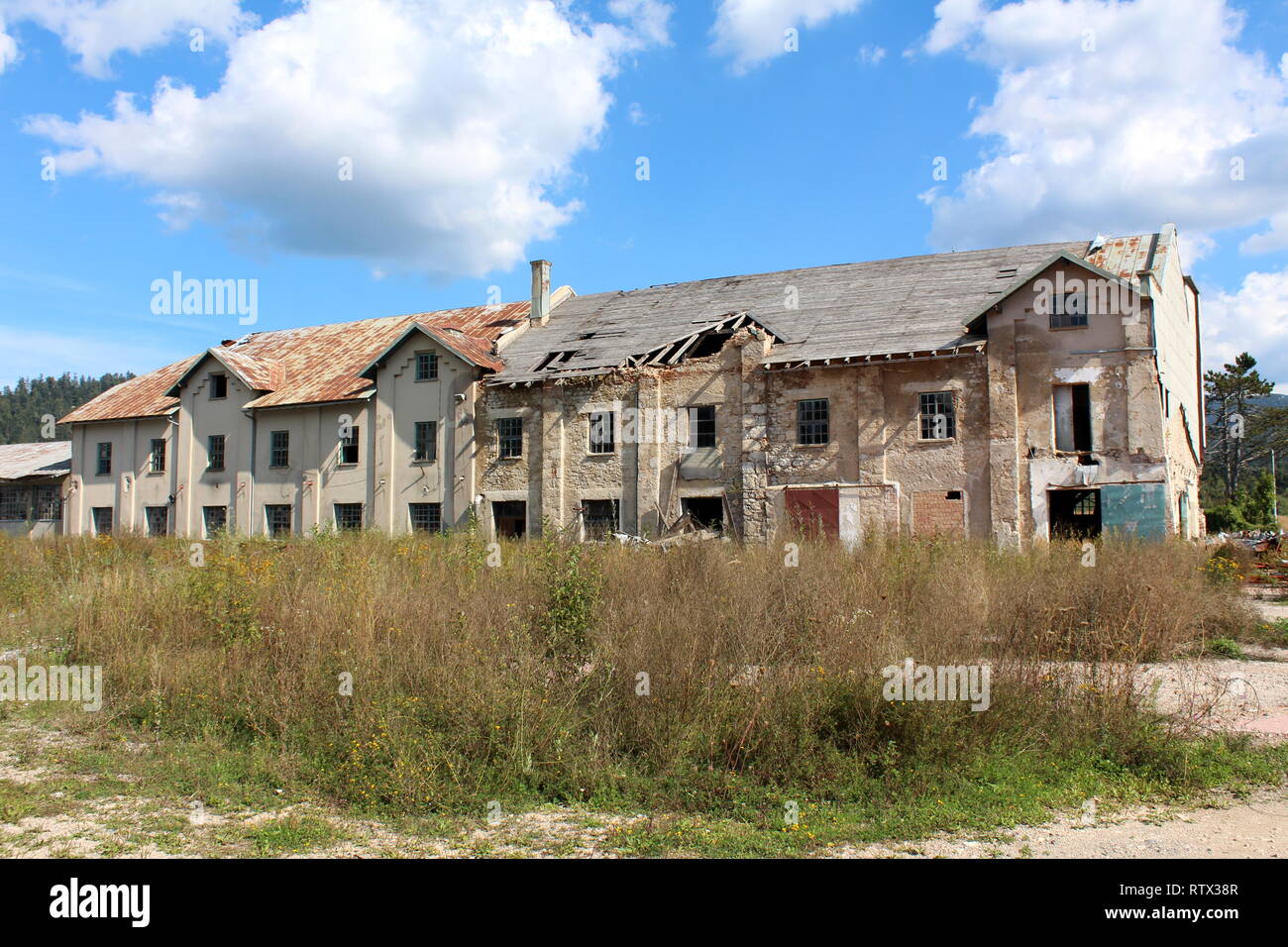 Large abandoned factory building with cracked dilapidated facade and ...