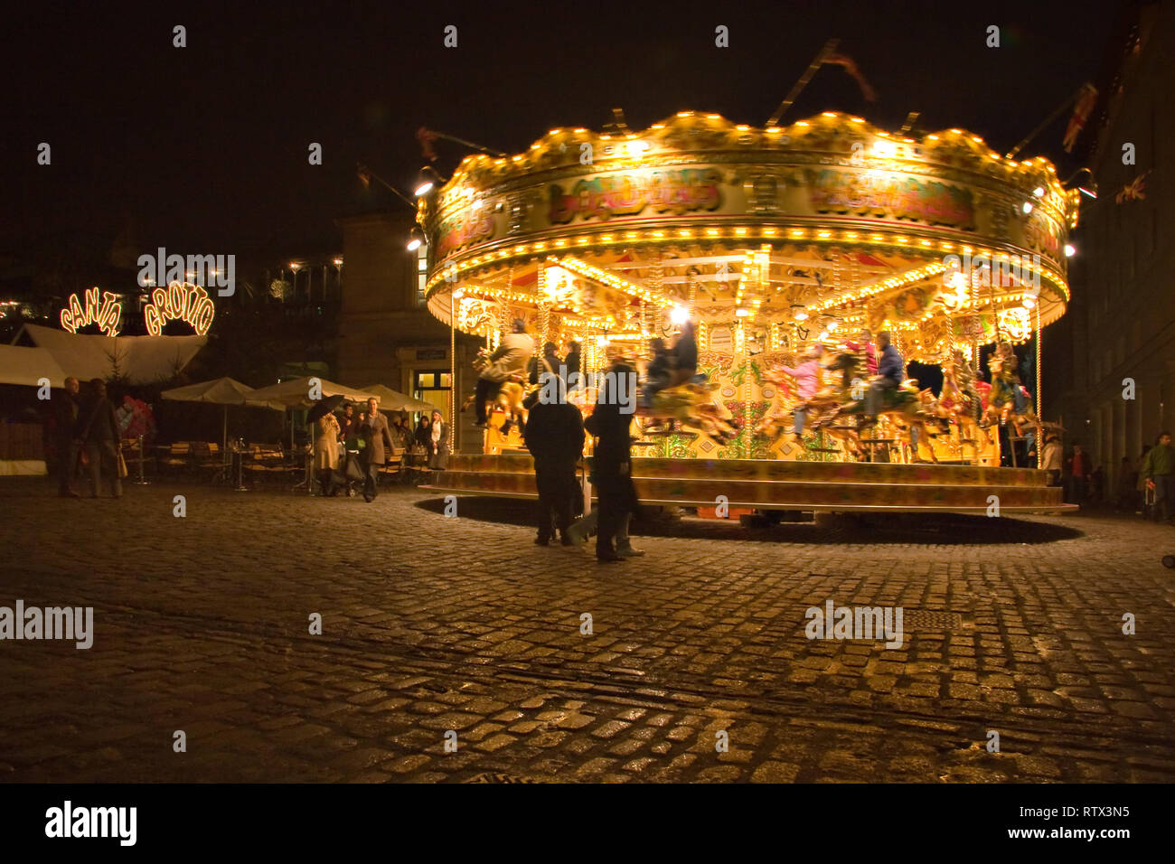 London, United Kingdom - November 25th, 2006: People walking around and watching carousel illuminated in evening at Covent Garden which is popular tou Stock Photo