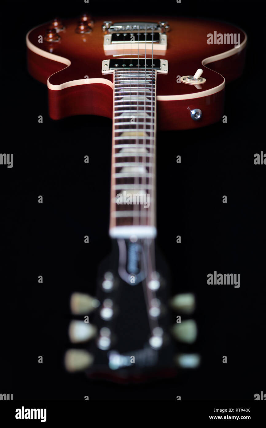 Headstock, machine head tuners and body of a new cherry red Gibson Les Paul Traditional electric guitar with focus on the body and headstock blurred. Stock Photo
