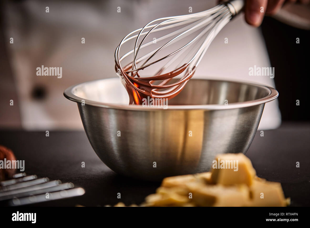 Chef preparing melted chocolate in a mixing bowl using an old fashioned