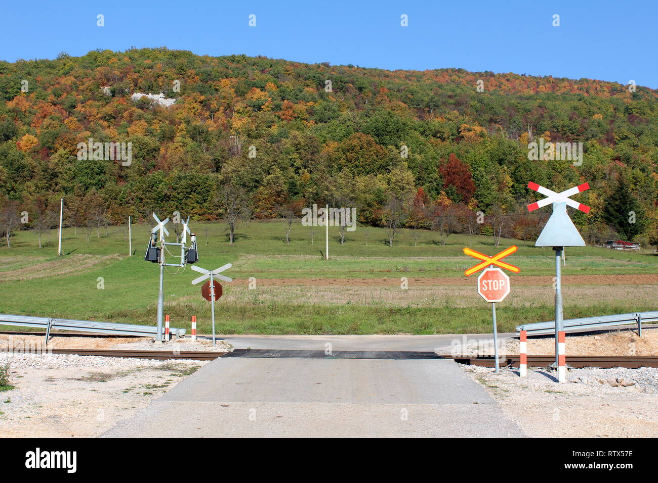 Railroad tracks crossing paved road surrounded with stop and warning