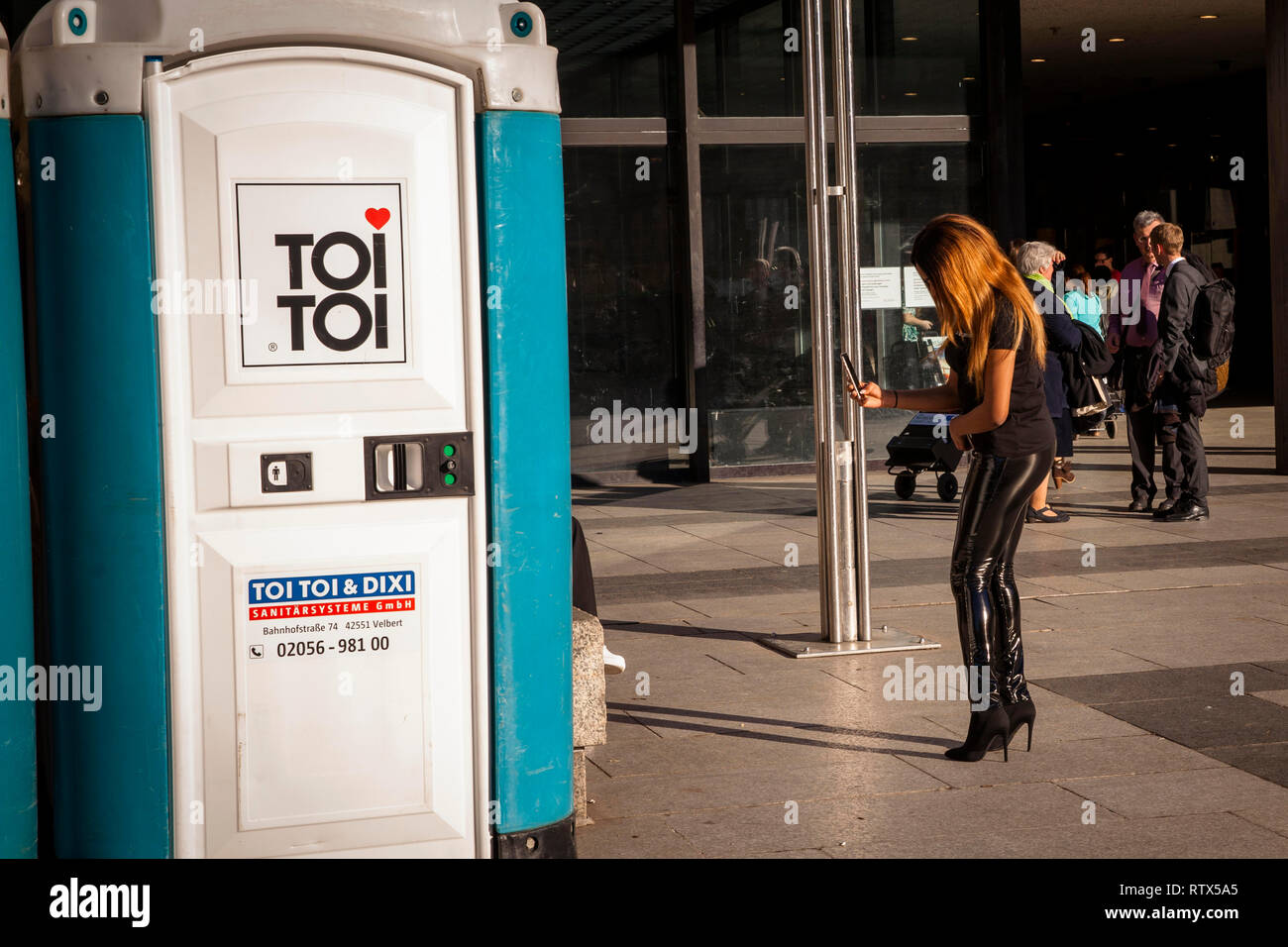 portable toilet in front of the Romano-Germanic Museum at the Roncalli square, woman with High Heels, Cologne, Germany.  Dixi Toilette vor dem Roemisc Stock Photo
