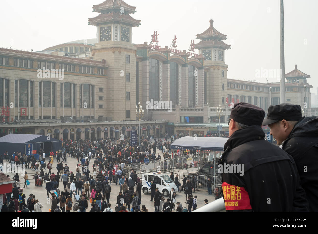 Two security men watch the crowd in Beijing railway station. China bans 23m from buying travel tickets as part of 'social credit' system 03-Mar-2019 Stock Photo