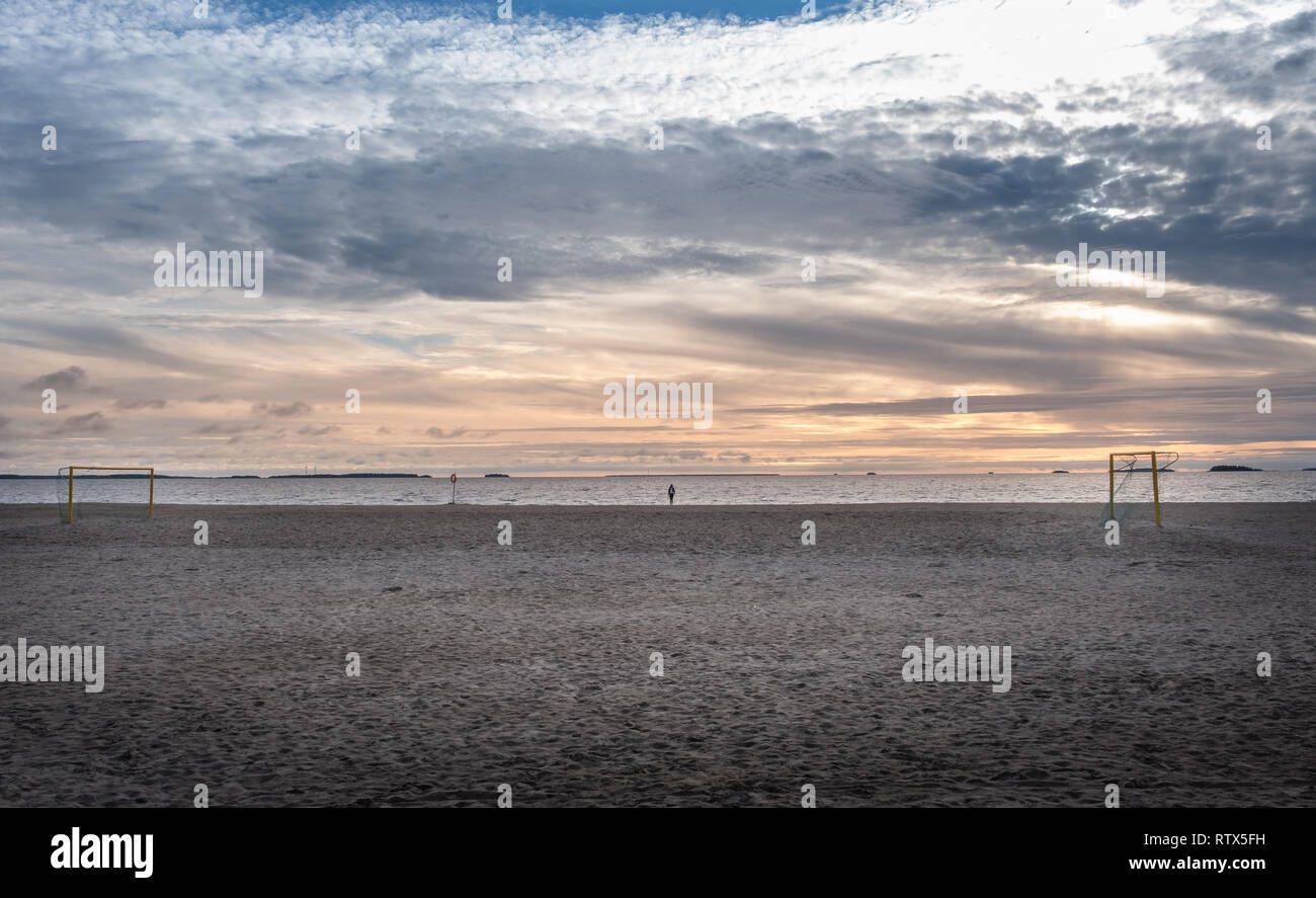 Lonely person standing in emtpy beach with football goals at summer evening in Finland. Stock Photo