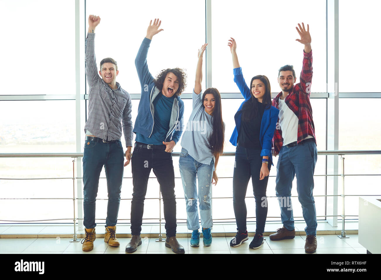Young people raised hands up against the window Stock Photo
