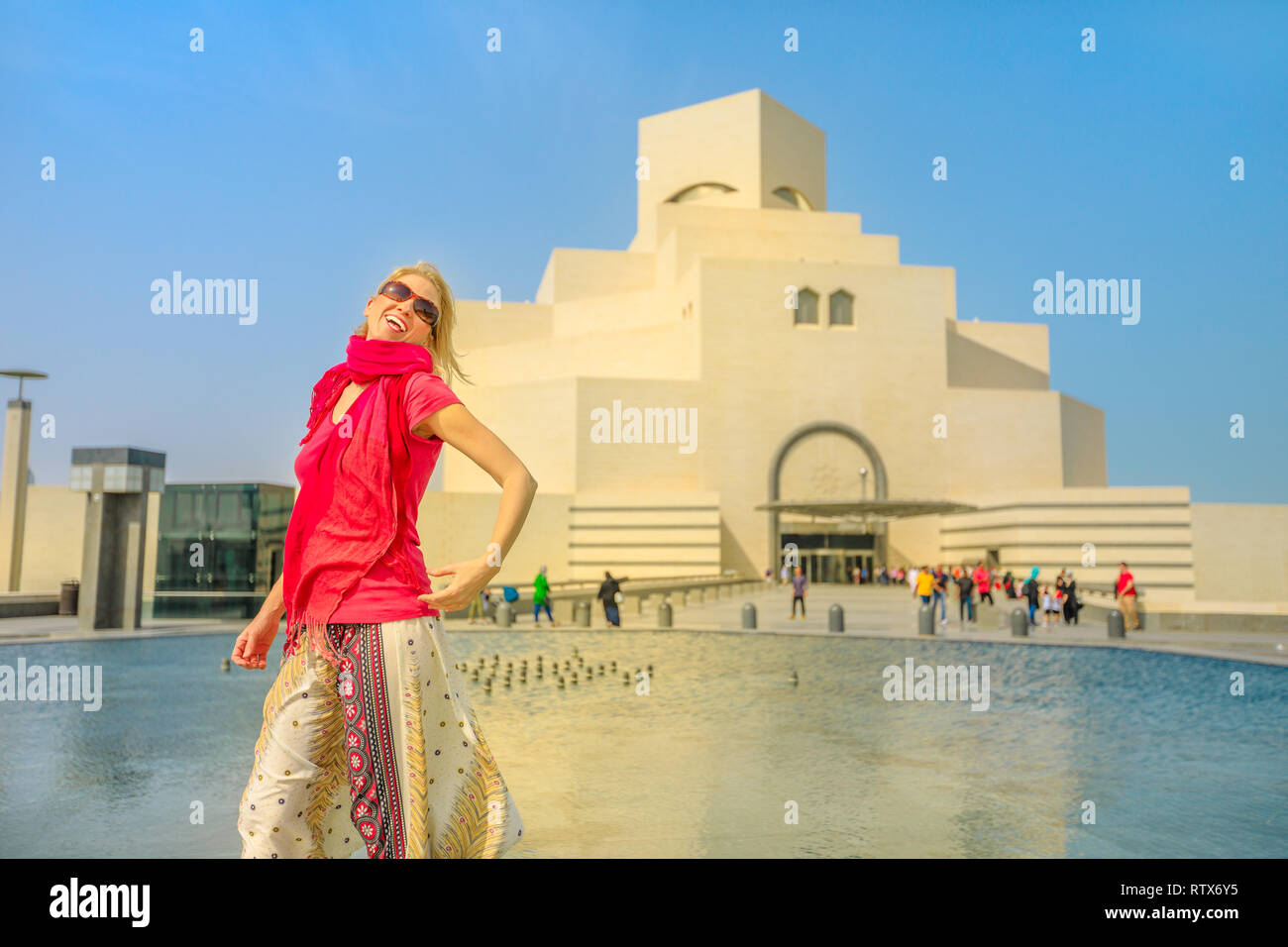 Happy woman in front of famous museum located along the Corniche near Dhow Harbor in Qatari capital. Caucasian tourist enjoying in Doha, Middle East Stock Photo
