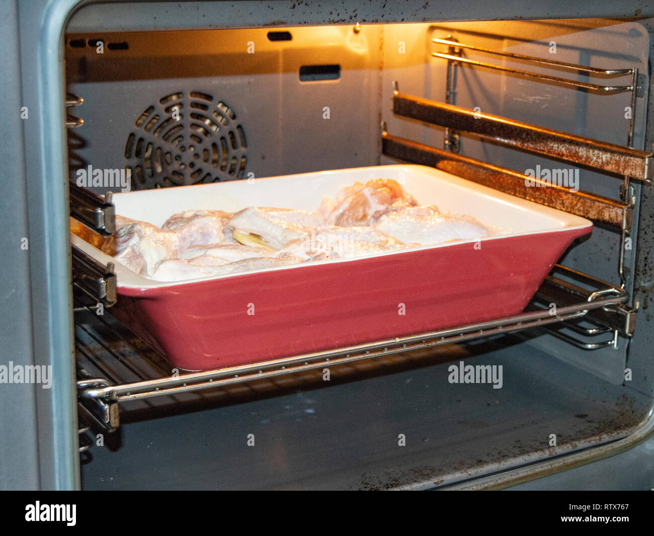 Delicious homemade roast with chicken and potatoes, raw ingredients in a ceramic pan in a hot