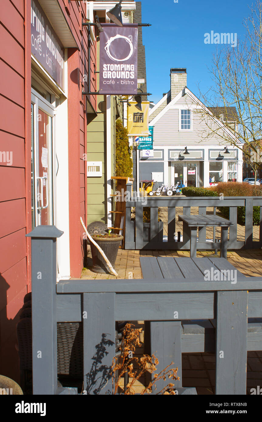 Side view of the front of a local bistro showing a grey fence and neighboring businesses. Stock Photo