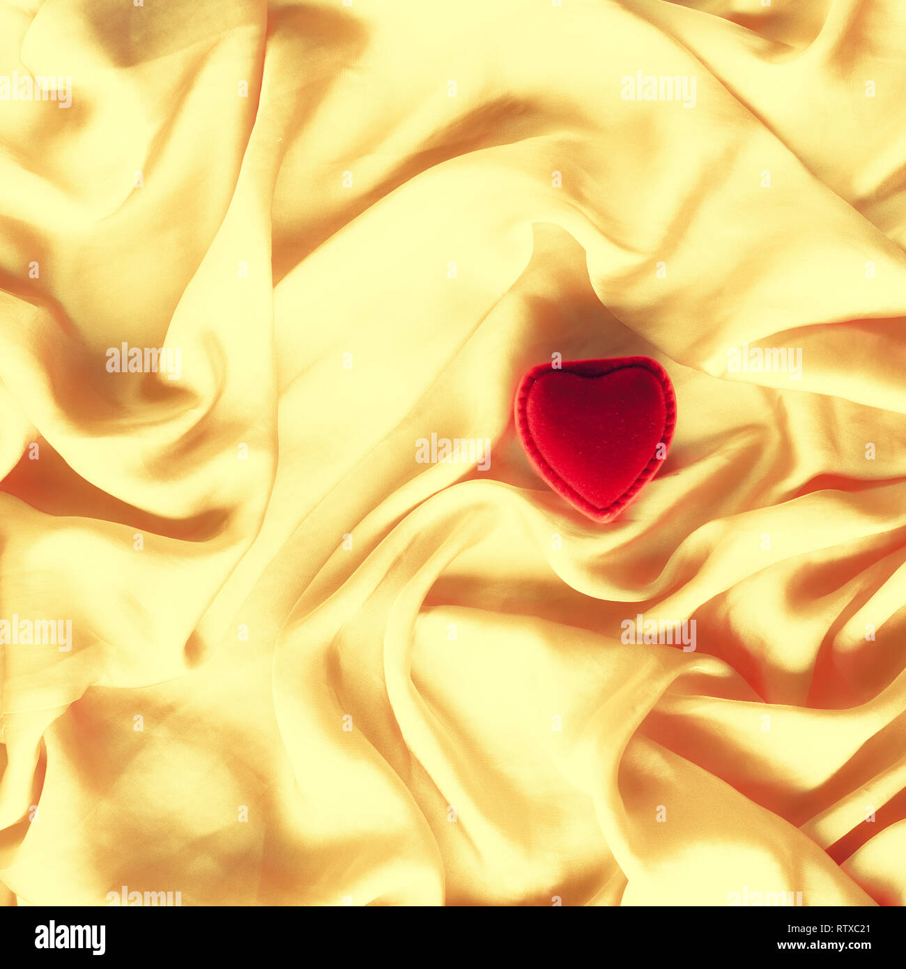 Red heart shaped jewellery gift box on golden silk Valentine's day, true love, engagement and