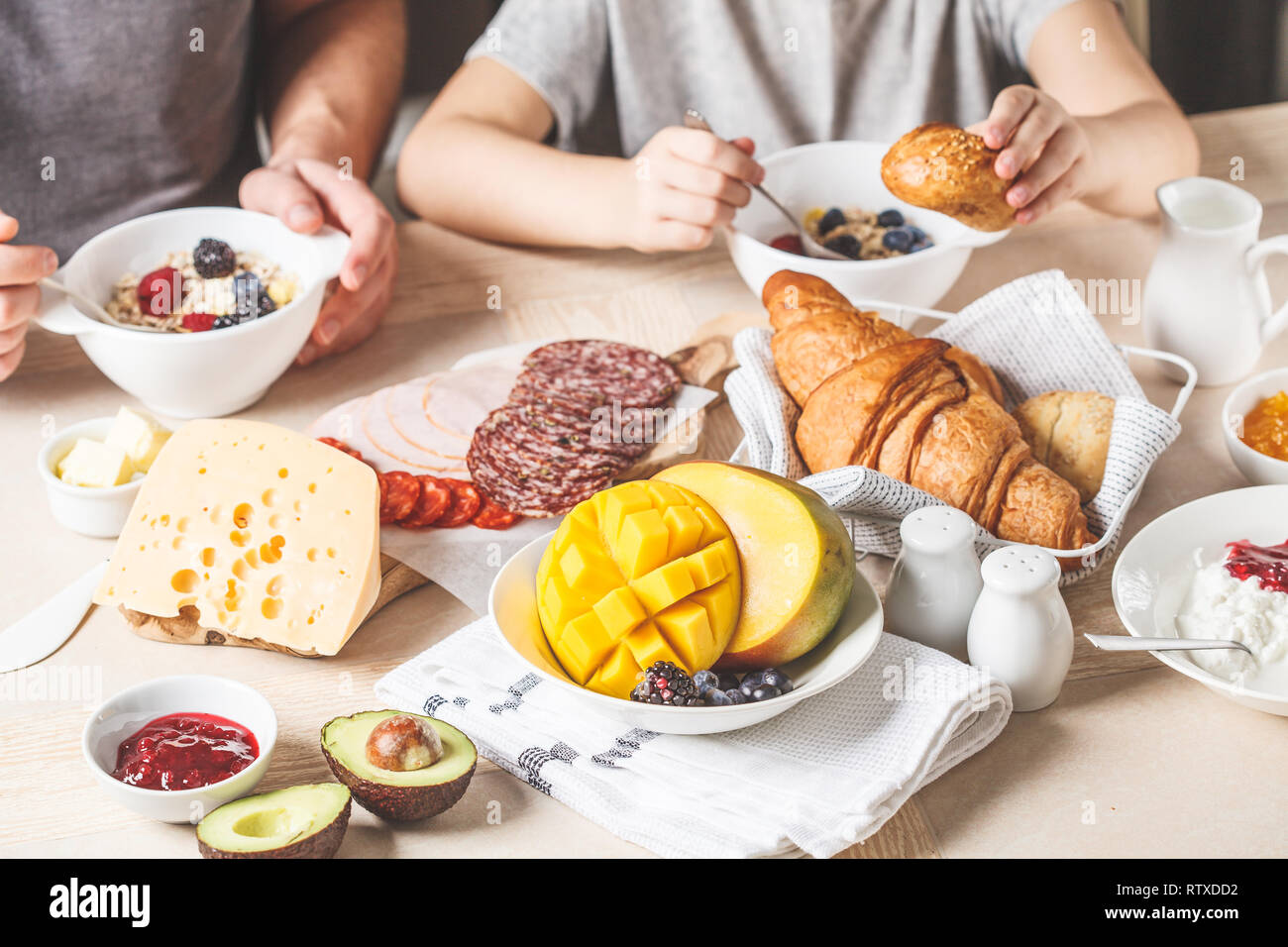 Continental breakfast table with croissants, jam, ham, butter, granola and fruit. Top view, food background. Stock Photo