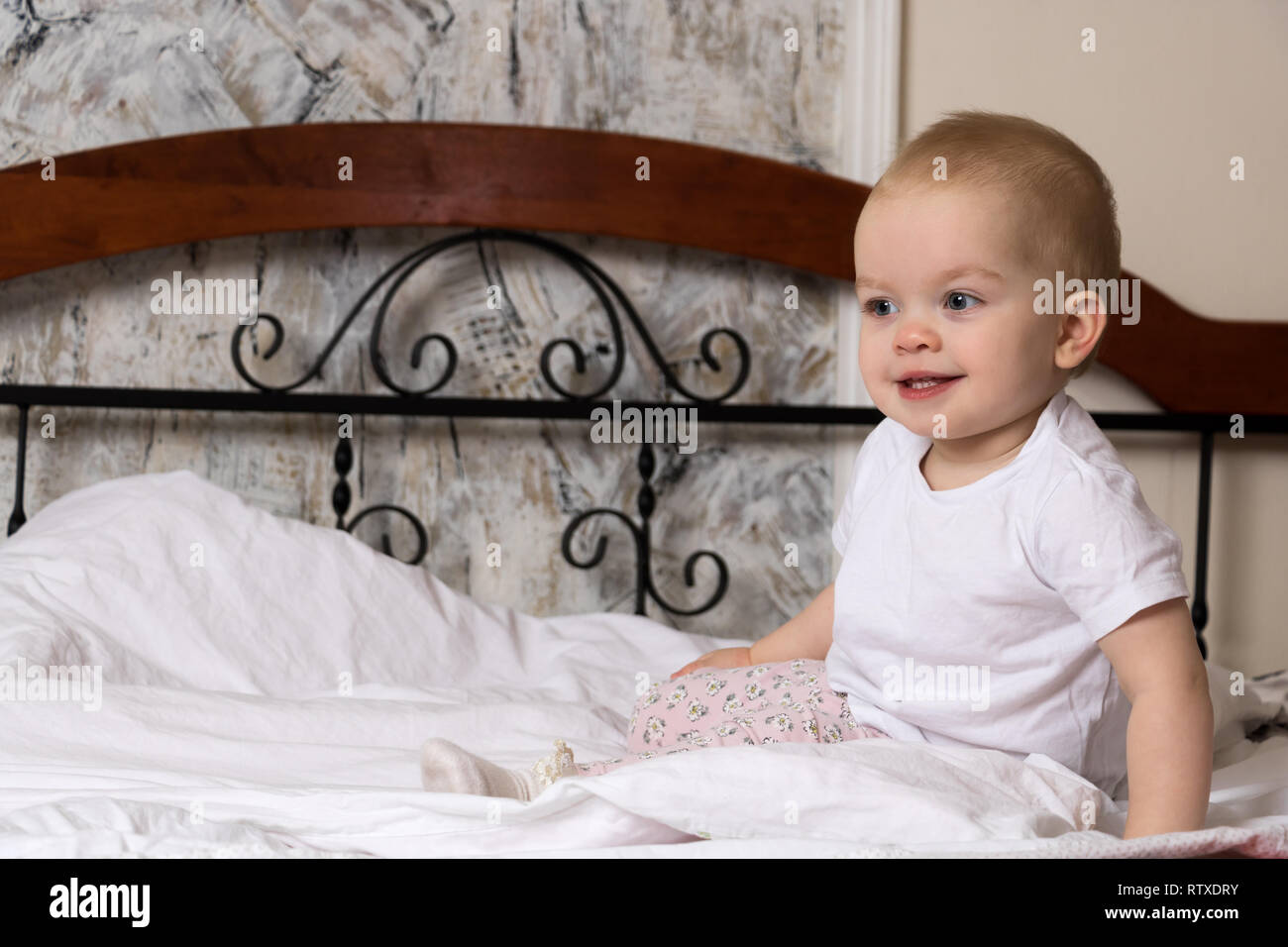 the baby is sitting on the bed and smiling cute Stock Photo - Alamy