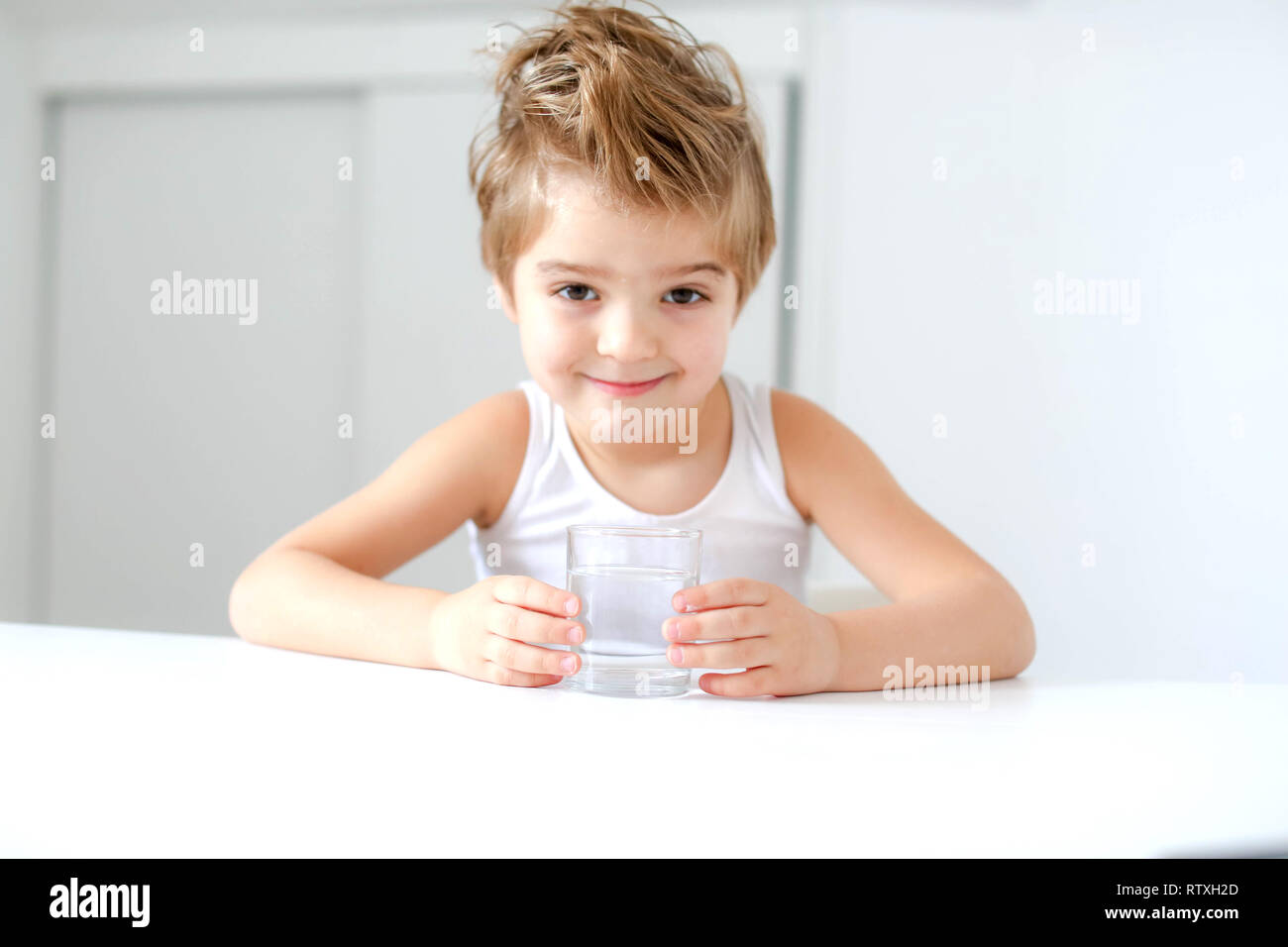 Cute smiling boy with glass of water isolated on a white background. Stock Photo