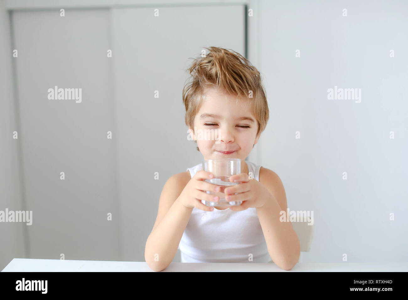 Cute smiling boy with glass of water isolated on a white background. Stock Photo