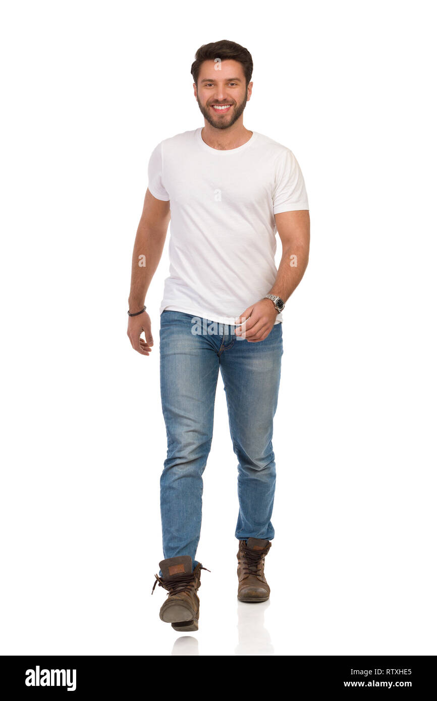 Smiling man in boots, jeans and white t-shirt is walking forward. Front  view. Full length studio shot isolated on white Stock Photo - Alamy