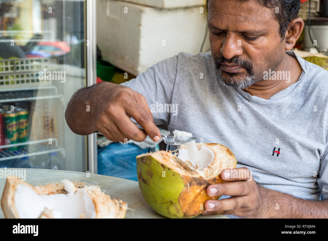 Man Eating Coconut Pulp after Drinking Coconut Water, Kuala Lumpur, Malaysia. Stock Photo