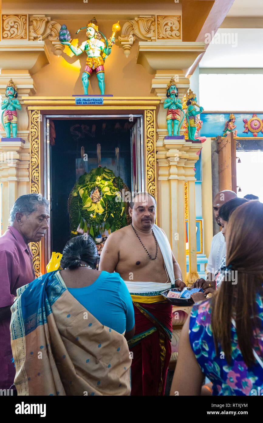 Hindu Priest Receiving Donations in front of Sri Anjaneyar Shrine, Kuil Sri Krishna Hindu Temple, Kuala Lumpur, Malaysia. Stock Photo