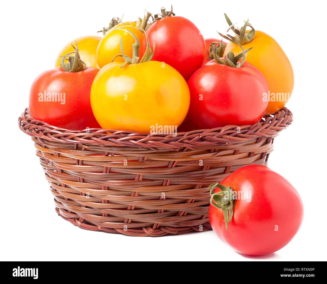 red and yellow tomatoes in a wicker basket isolated on white background ...