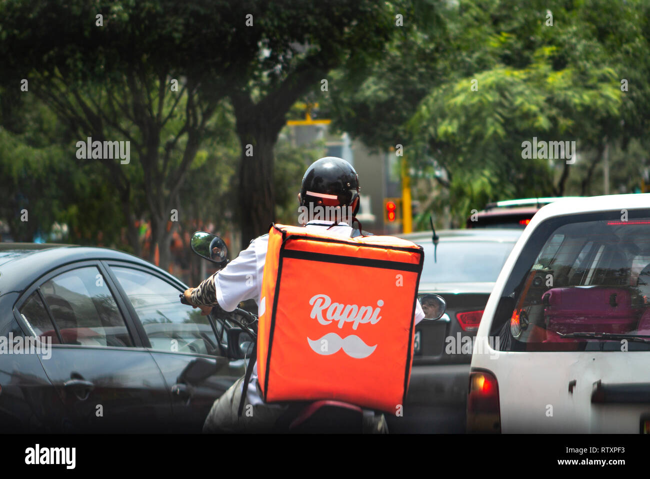 Lima, Peru - February 17 2019: Rappi driver food delivery service stuck in traffic jam. Sharing collaborative economy concept in South America. Stock Photo