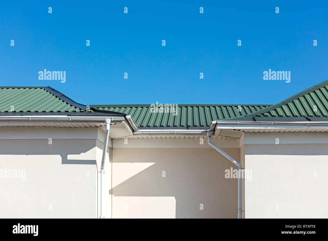 white metal rain gutter system on roof top of new house against blue