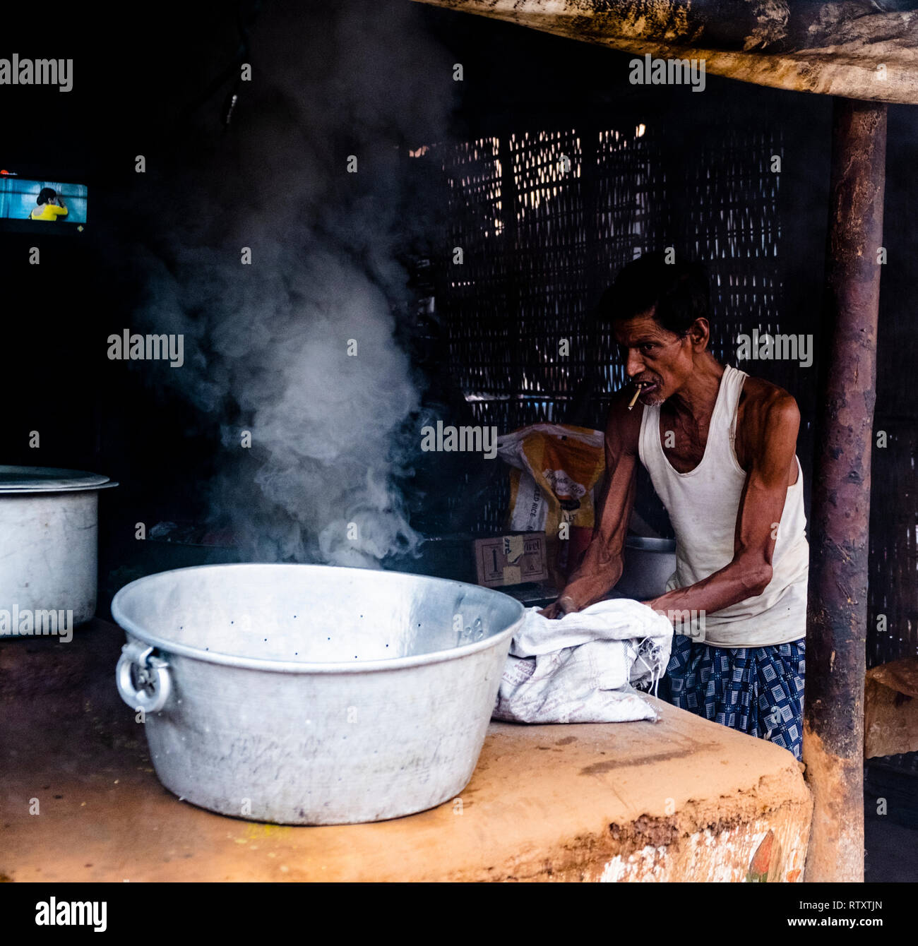 A man igniting coal to prepare dinner at a Dhaba at Sahid Nager Hata, Bhubaneshwar. Stock Photo
