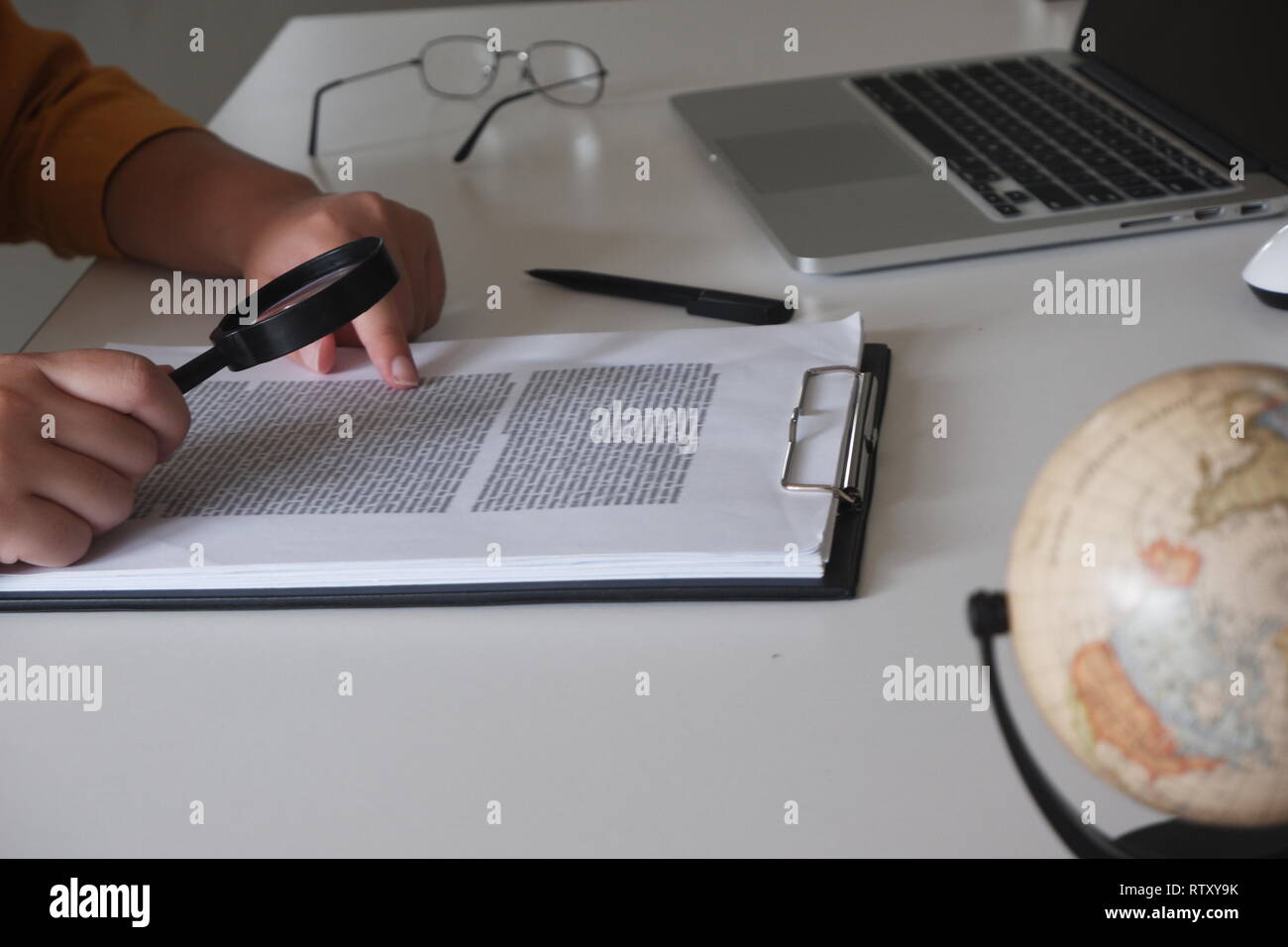 Businesswoman looking through a magnifying glass to documents note in the office Stock Photo