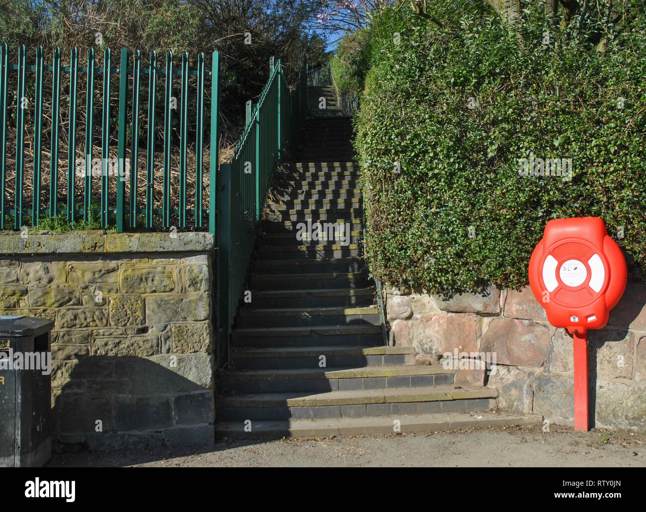 Steps leading upwards from a path alongside a river showing emergency life ring and litter bin Stock Photo